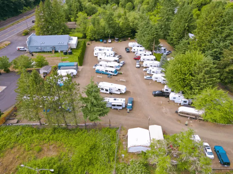 An aerial view of Maple Lane RV Park and Marina, east of Florence on the Oregon Coast, showing numerous RVs parked on dirt lots surrounded by lush green trees.