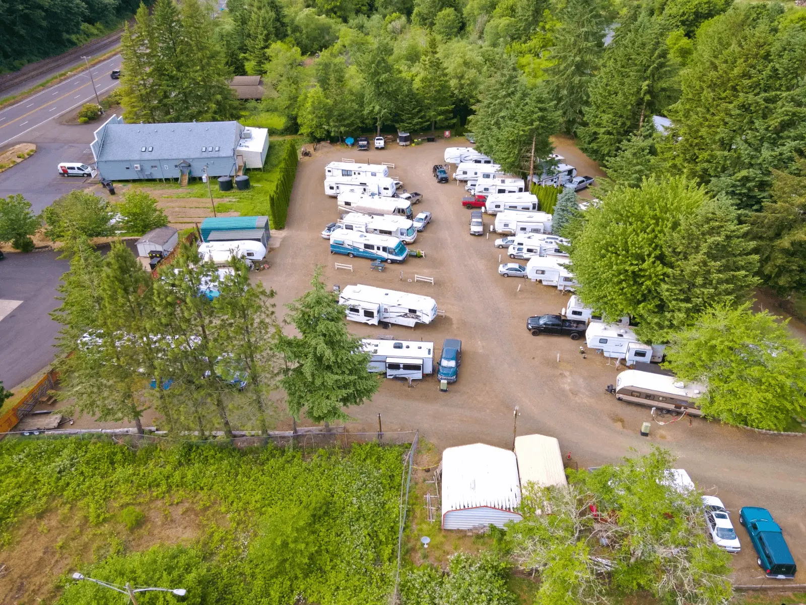 An aerial view of Maple Lane RV Park and Marina, east of Florence on the Oregon Coast, showing numerous RVs parked on dirt lots surrounded by lush green trees.