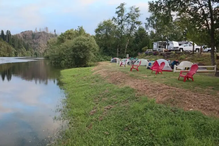 A scenic view of Maple Lane RV Park and Marina on the Oregon Coast, with tents and RVs along a calm river.